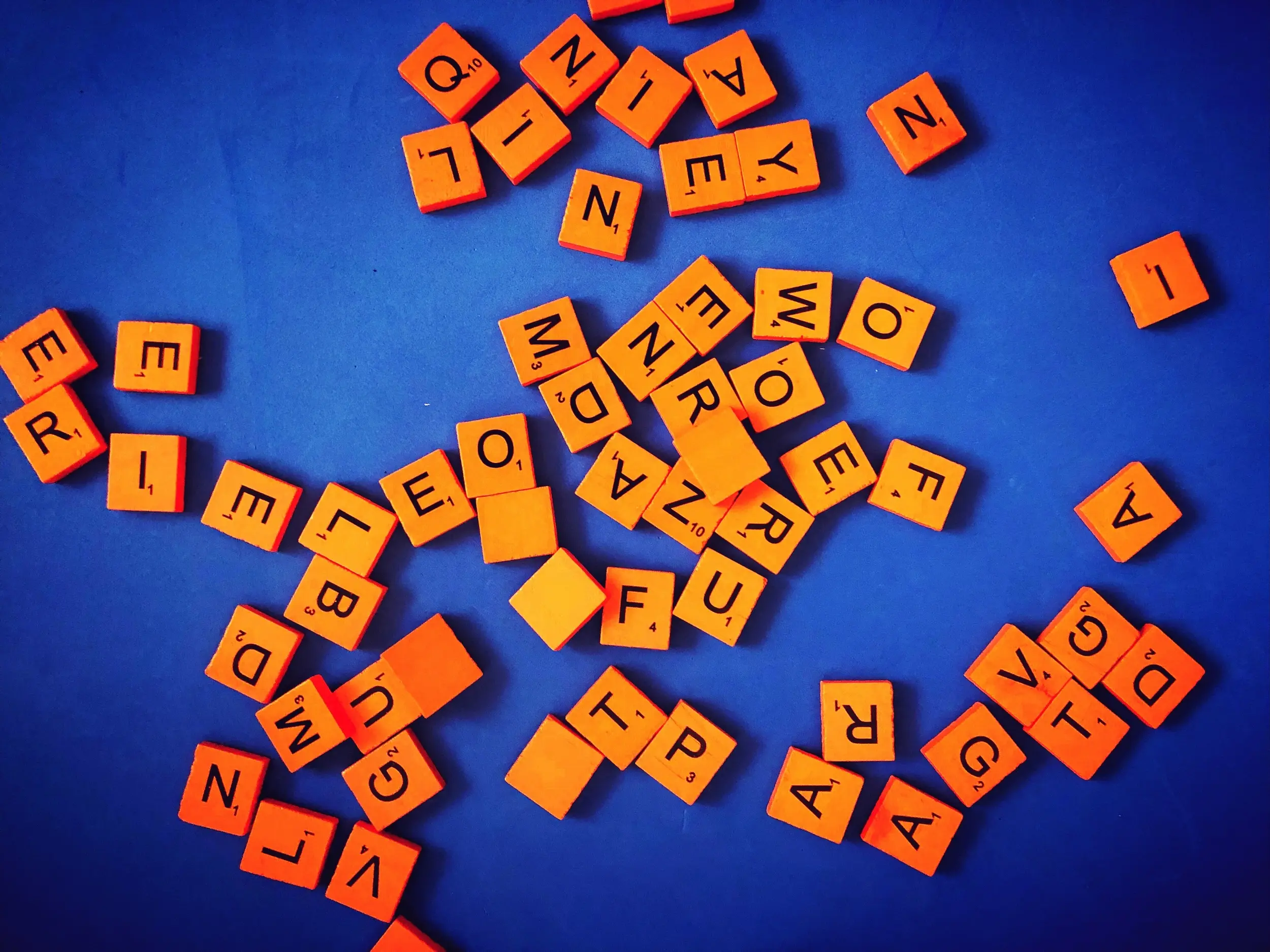 Scattered orange Scrabble letters on blue background