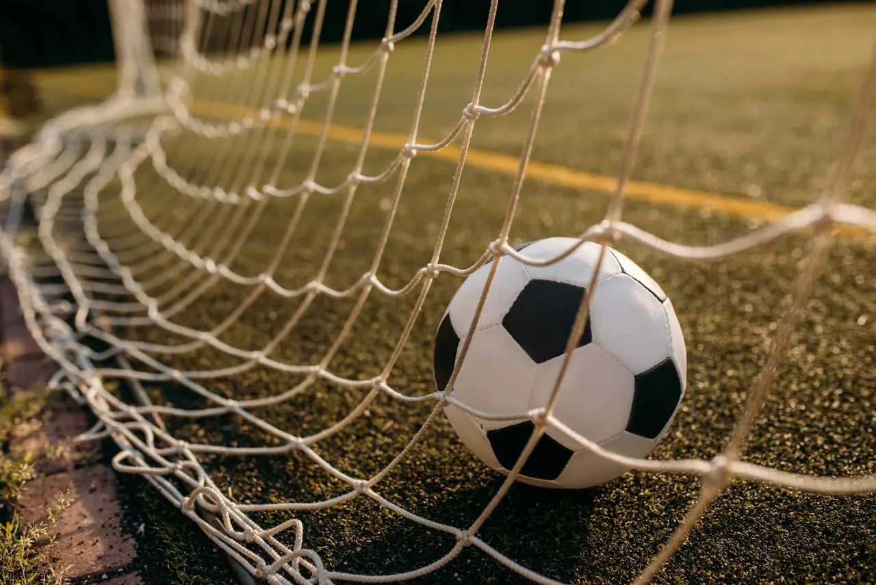 A soccer ball resting at the back of a net 