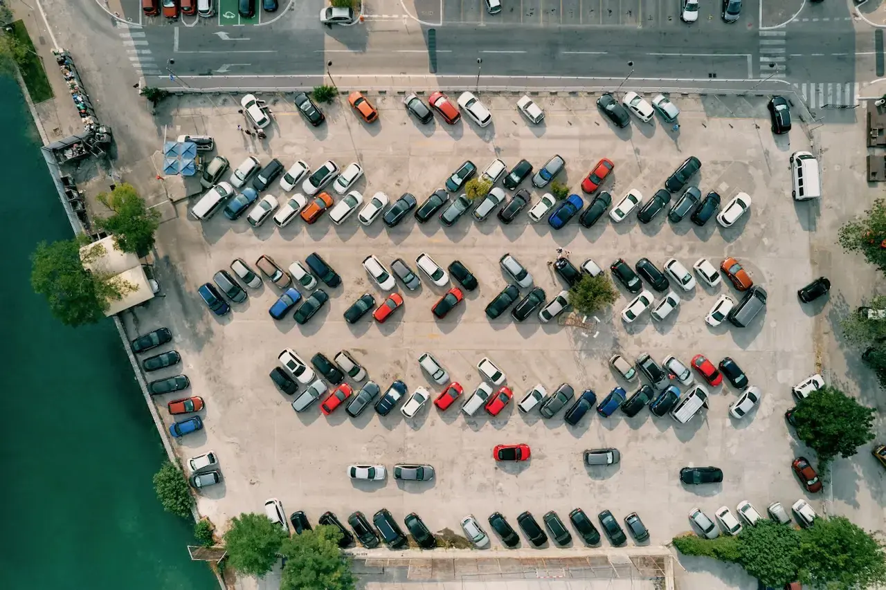 An overhead shot of a parking lot with cars spaced throughout it 