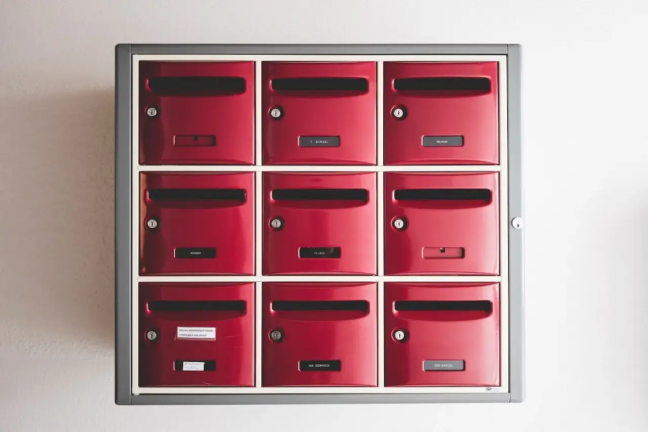 A set of nine red mailboxes in a three by three grid, with mail slots in each