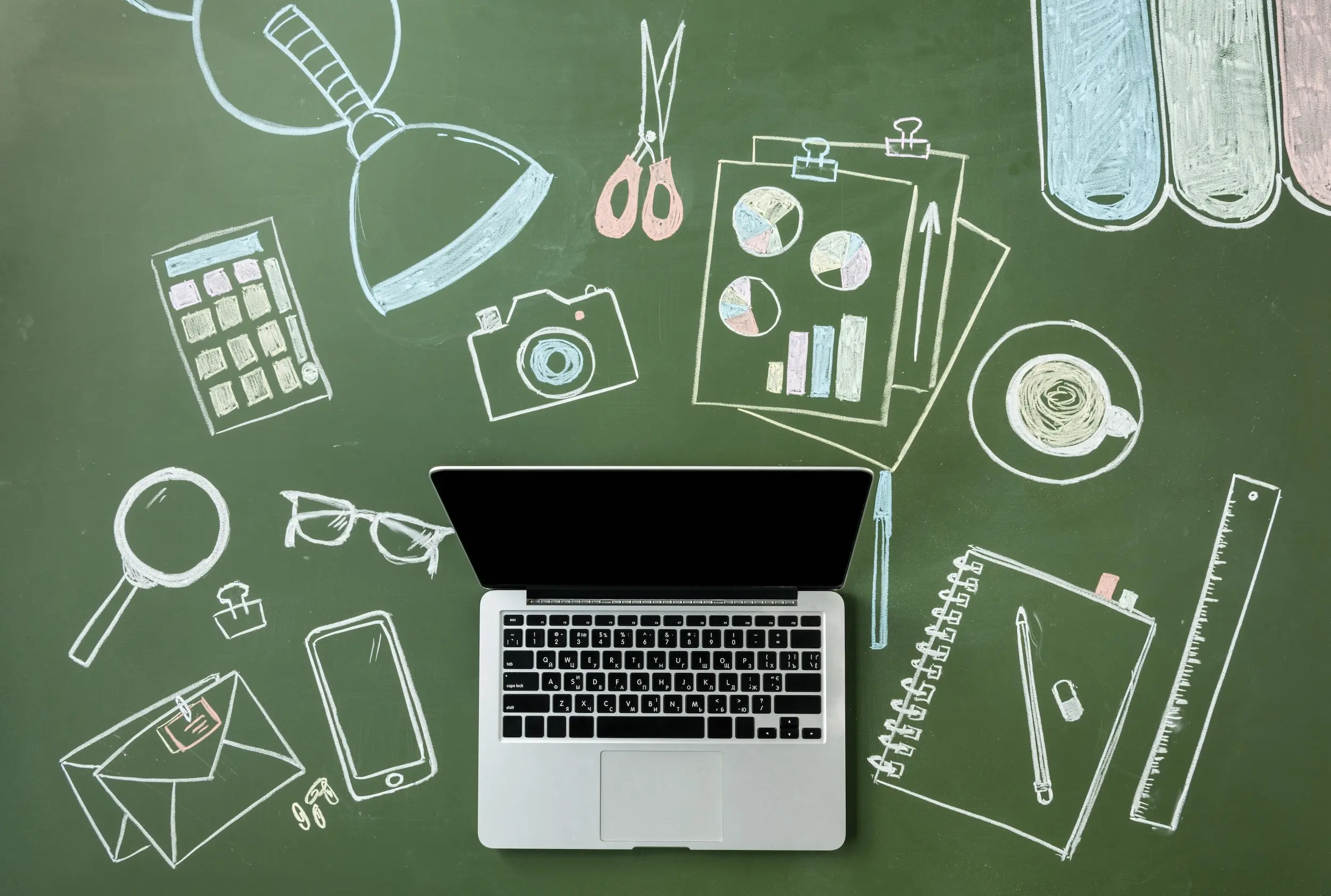 Top view of laptop computer and pictures on green board, small office concept