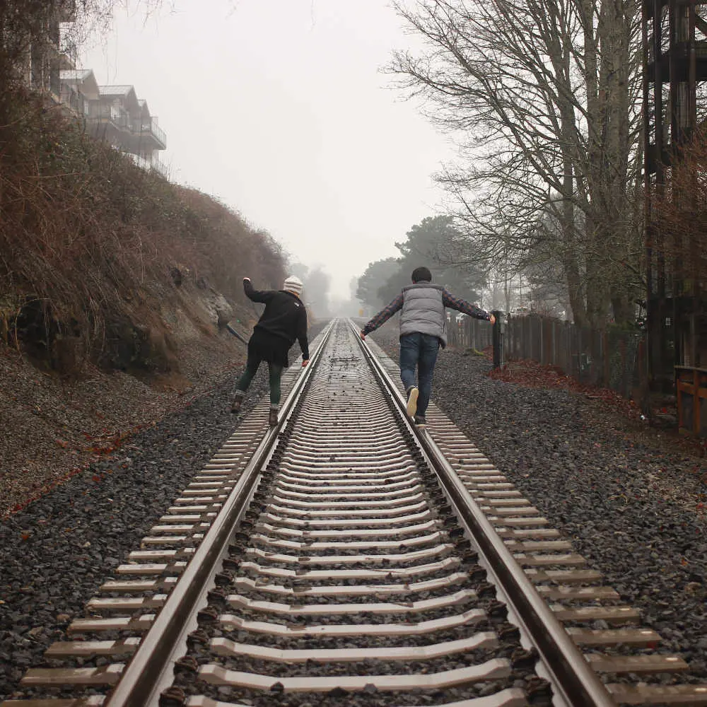 Two people walking on railroad