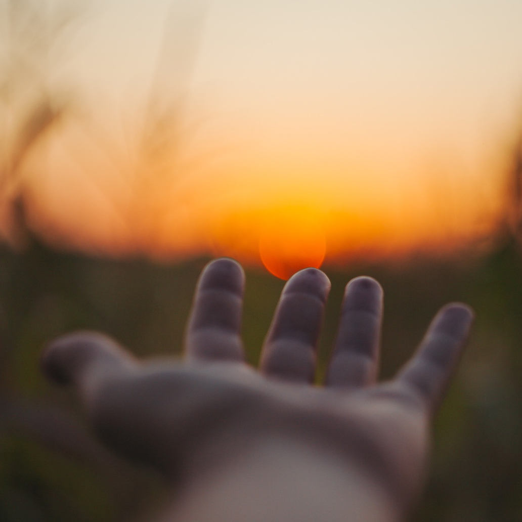 Hand reaching toward the sun