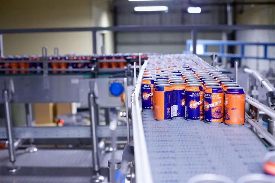Orange and blue beer cans coming off a conveyor belt to be filled.