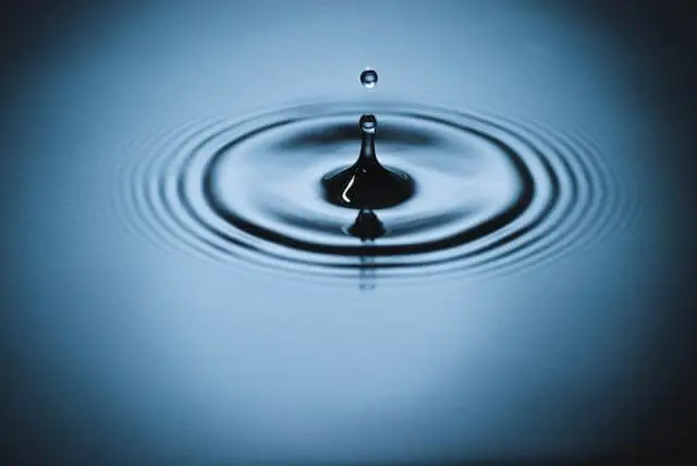 A drop of water hitting a larger pool of water, creating ripples