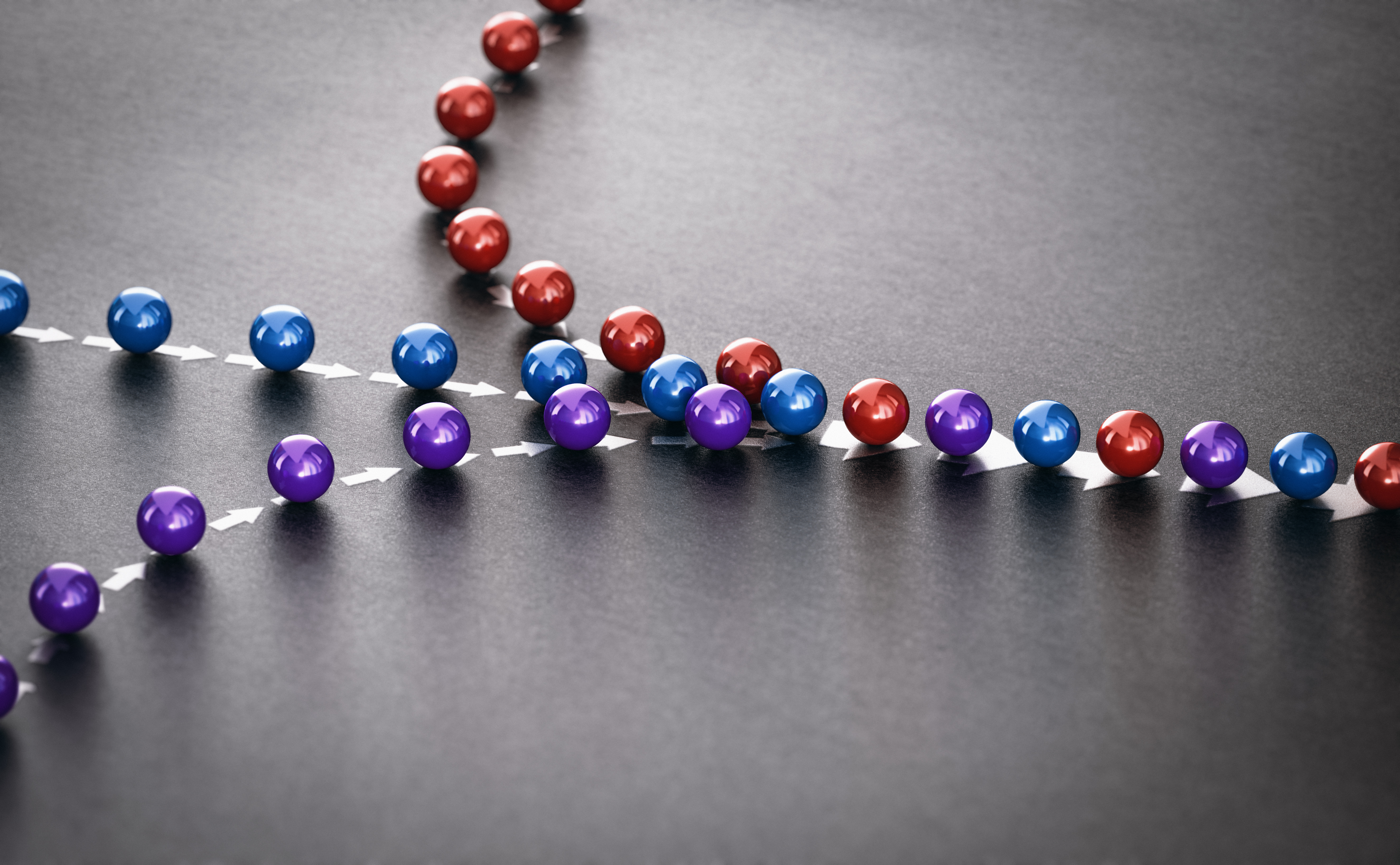 Three lines of red, blue, and purple balls converging into one line going in the same direction.