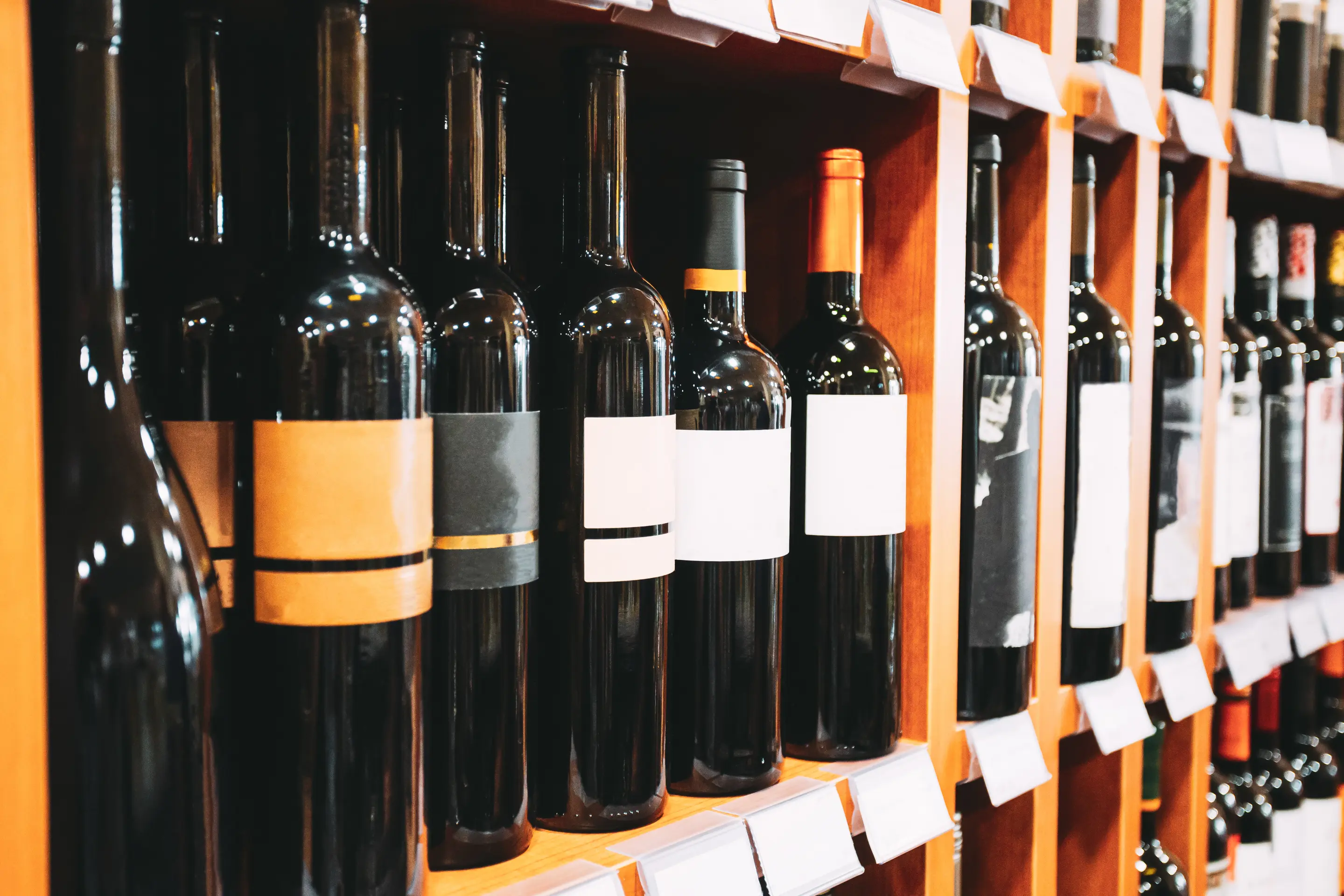 A store shelf with bottles of wine and price tags
