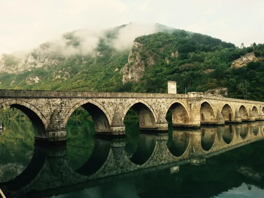 The Mehmed Paša Sokolović Bridge is a stone bridge in Višegrad, Bosnia and Herzegovina, and was completed in 1577. Photo by Torsten Muller, found at https://unsplash.com/photos/tfoqHmi-MOg