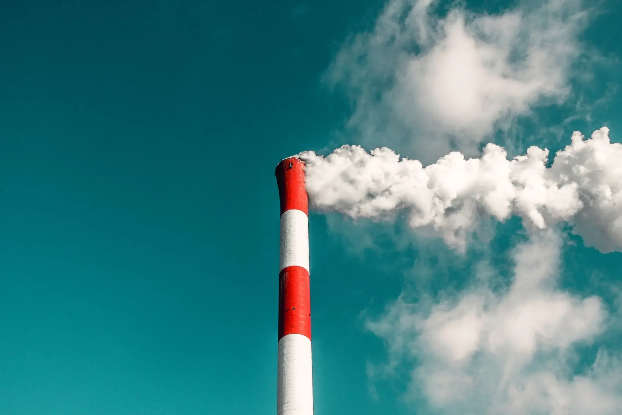 Photograph of a smoke stack with white smoke billowing out.